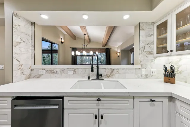 a large kitchen with stainless steel appliances granite countertop a stove top oven a sink dishwasher and white cabinets with wooden floor