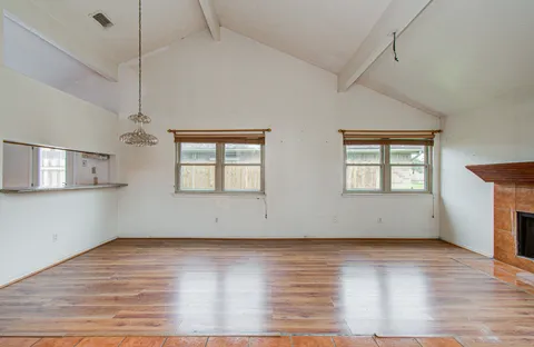 an empty room with wooden floor and windows