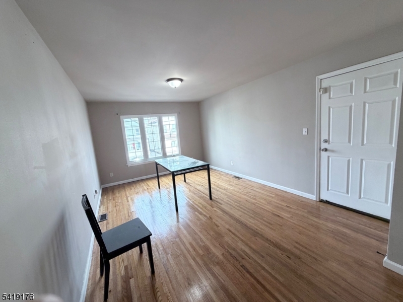1036 Flora Street, Unit 1 Elizabeth, NJ 07201 - Photo 3 of 10 a view of an empty room with wooden floor and a window