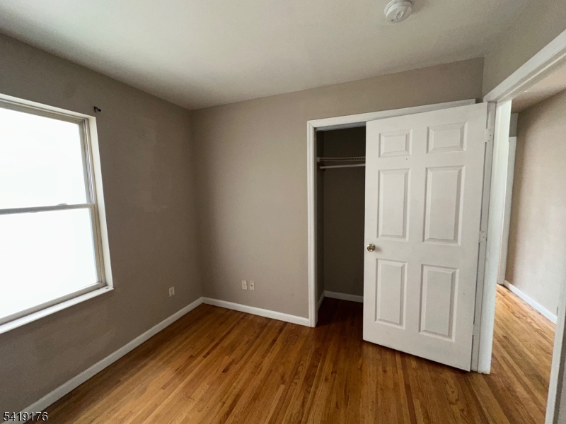 1036 Flora Street, Unit 1 Elizabeth, NJ 07201 - Photo 10 of 10 an empty room with wooden floor and windows