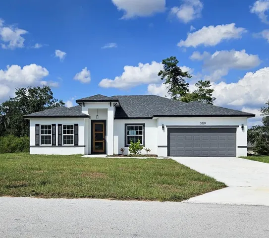 a front view of a house with a garden and trees