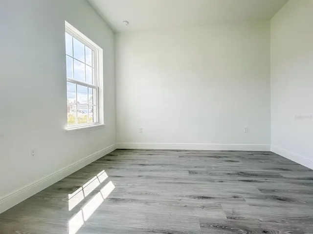a view of empty room with wooden floor and fan