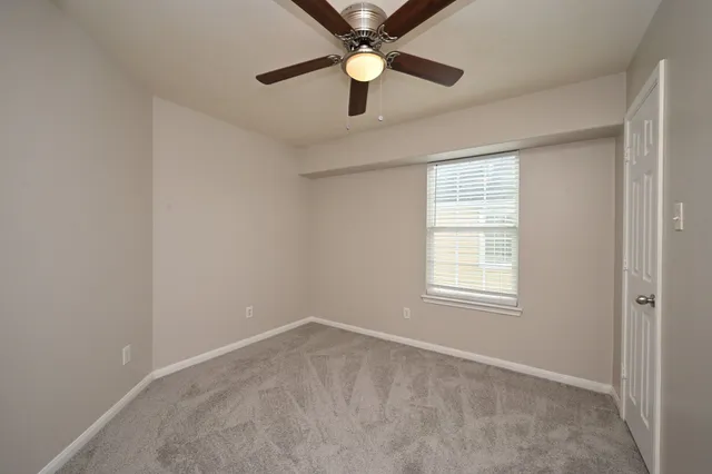 an empty room with a window and a fan