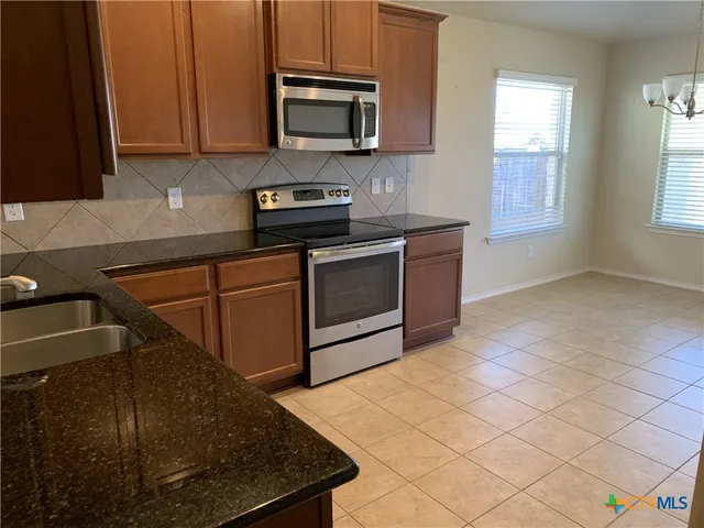 a kitchen with stainless steel appliances granite countertop a sink a stove and a microwave