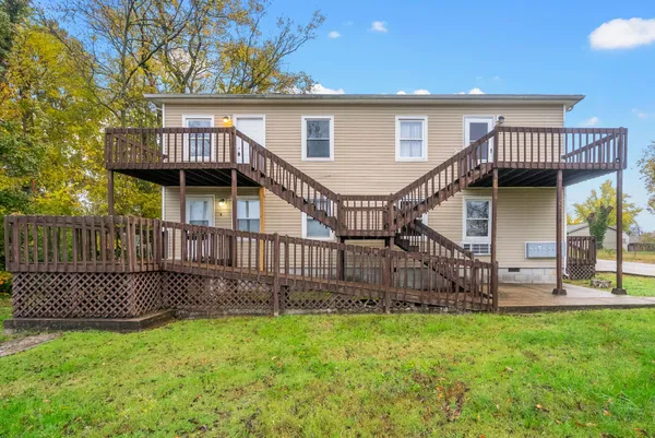 a view of a house with a wooden deck and a yard