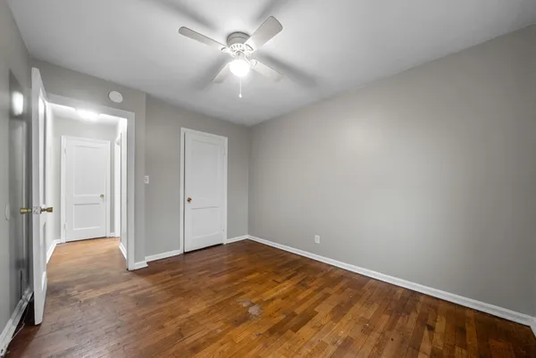 an empty room with wooden floor and fan
