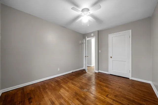 an empty room with wooden floor and fan