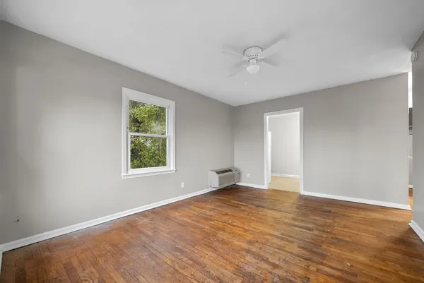 a view of an empty room with wooden floor and a window