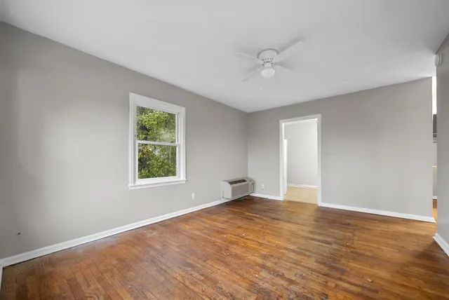 a view of an empty room with wooden floor and a window
