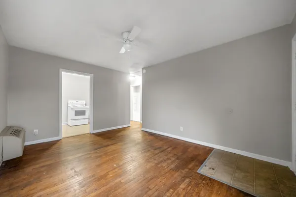 a view of an empty room with wooden floor and a window