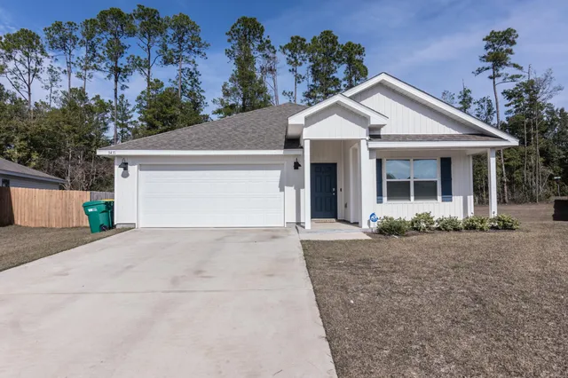a view of a white house with a yard and potted plants