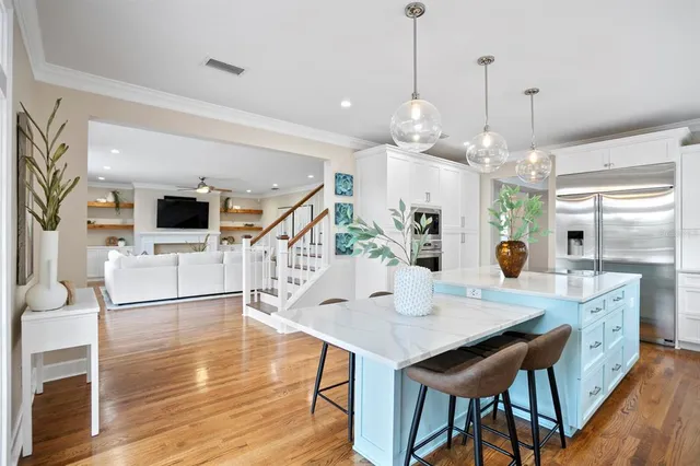 a open kitchen with stainless steel appliances granite countertop a dining table chairs sink and stove