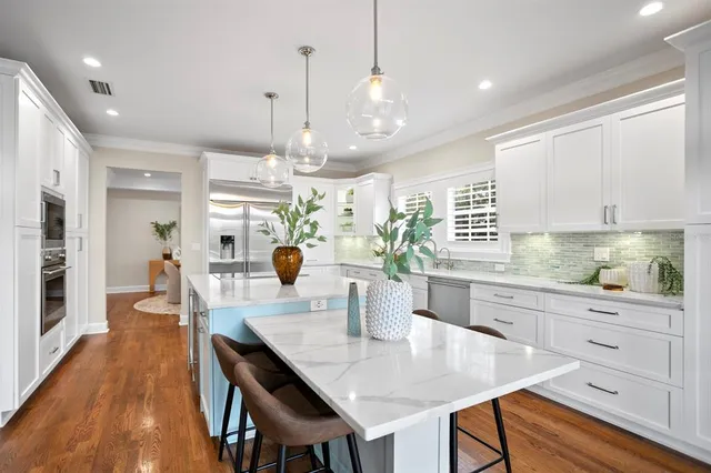 a kitchen with stainless steel appliances kitchen island granite countertop a table chairs and a refrigerator