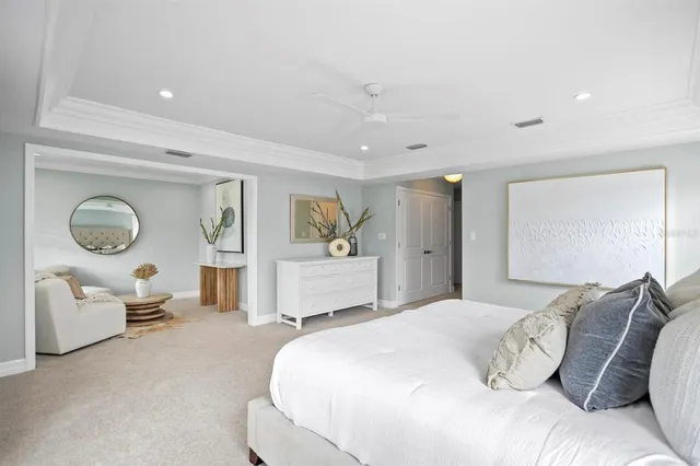 a spacious bedroom with a bed mirror painting on wall and a window