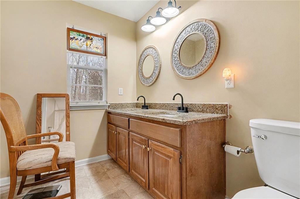 235 Cecil Jackson Road Griffin, GA 30223 - Photo 25 of 34 a bathroom with a granite countertop toilet a sink and a mirror