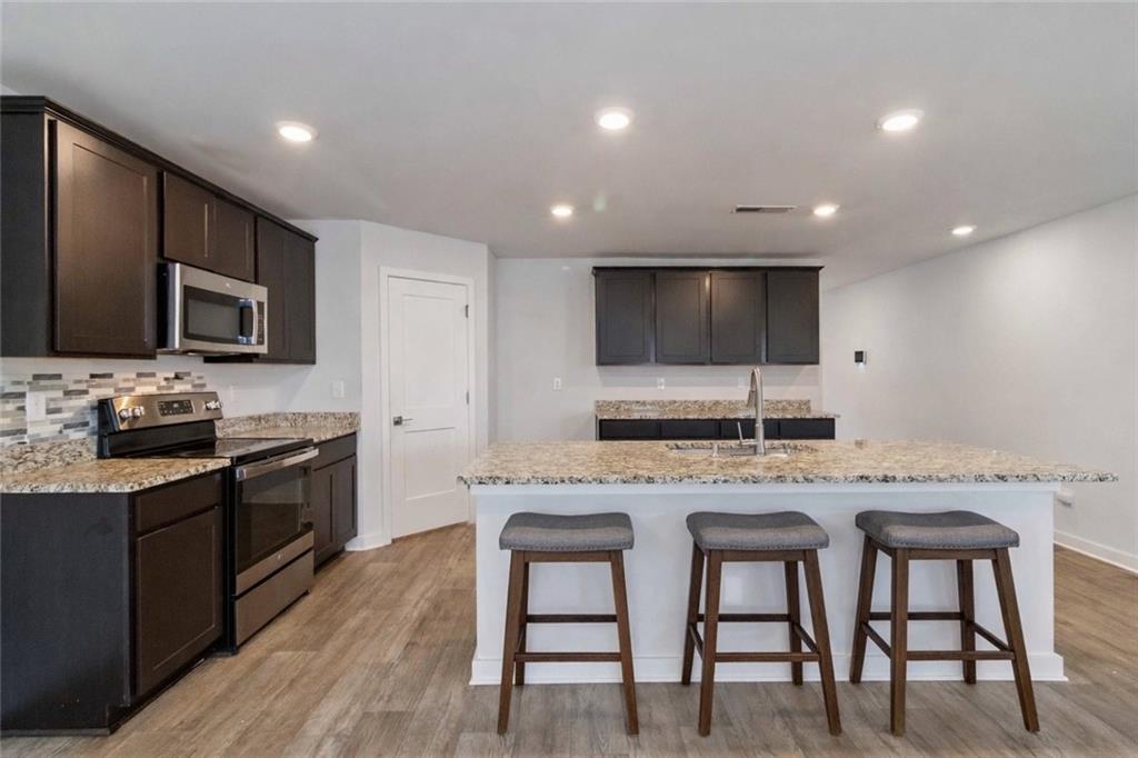 163 Kingfisher Walk Covington, GA 30014 - Photo 15 of 41 a kitchen with stainless steel appliances granite countertop a stove a sink a microwave a refrigerator and cabinets