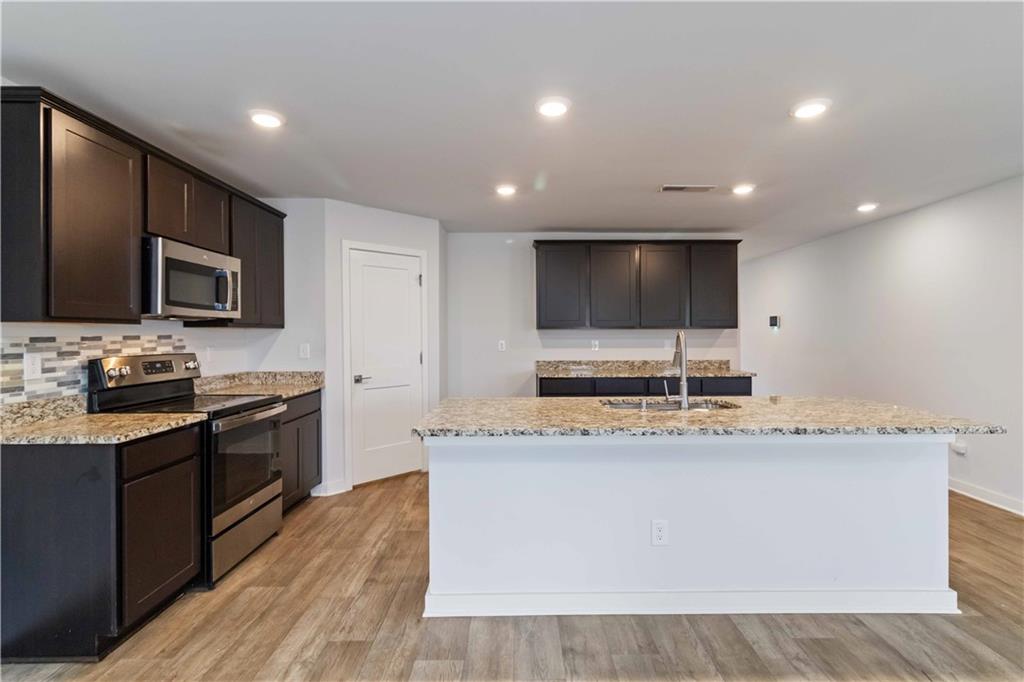 163 Kingfisher Walk Covington, GA 30014 - Photo 16 of 41 a large kitchen with stainless steel appliances a large counter top a stove a sink a refrigerator and a microwave