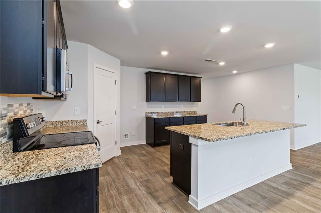 163 Kingfisher Walk Covington, GA 30014 - Photo 17 of 41 a kitchen with a sink and a stove top oven with wooden floor