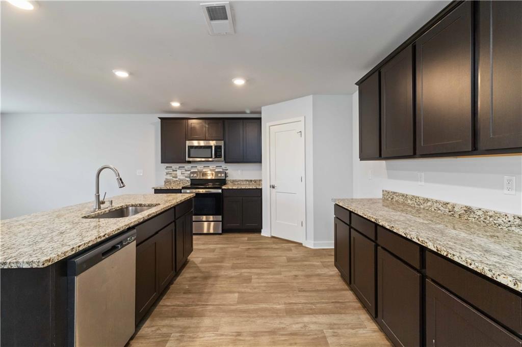 163 Kingfisher Walk Covington, GA 30014 - Photo 18 of 41 a kitchen with stainless steel appliances granite countertop a sink stove and refrigerator