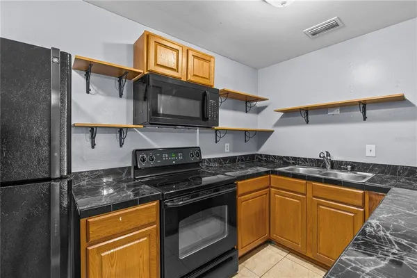 a kitchen with granite countertop a sink stove and microwave