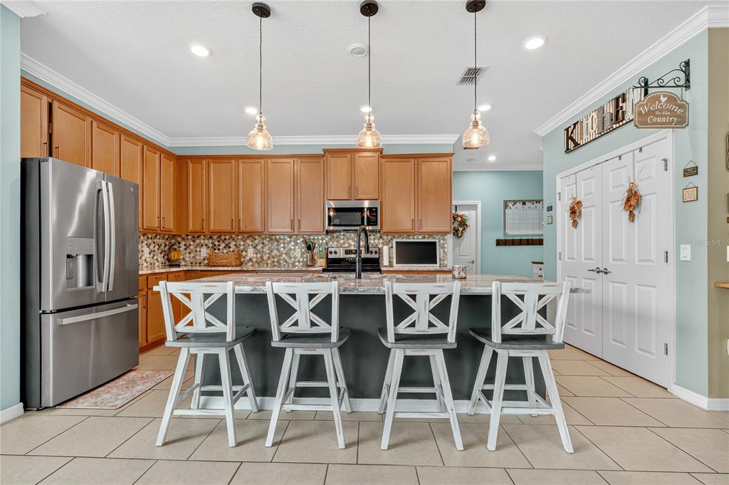 2899 Parkfield Road St. Cloud, FL 34772 - Photo 16 of 52 a kitchen with stainless steel appliances kitchen island granite countertop a dining table chairs and a refrigerator