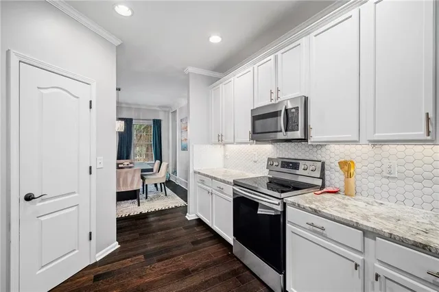 a kitchen with granite countertop a stove top oven a sink dishwasher and a refrigerator with wooden floor