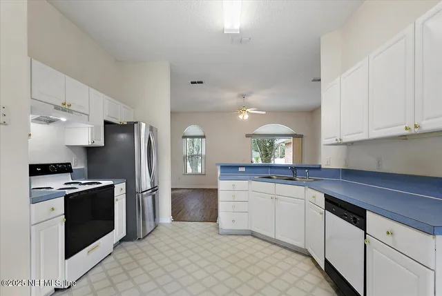 a kitchen with granite countertop white cabinets and stainless steel appliances