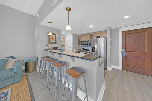 a kitchen with stainless steel appliances granite countertop a refrigerator a stove a sink dishwasher a dining table and chairs with wooden floor