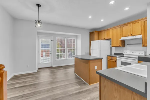 a kitchen with stainless steel appliances granite countertop a refrigerator a sink dishwasher a stove and white countertops with wooden floor