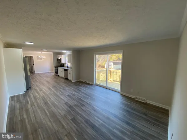 an empty room with wooden floor and a ceiling fan