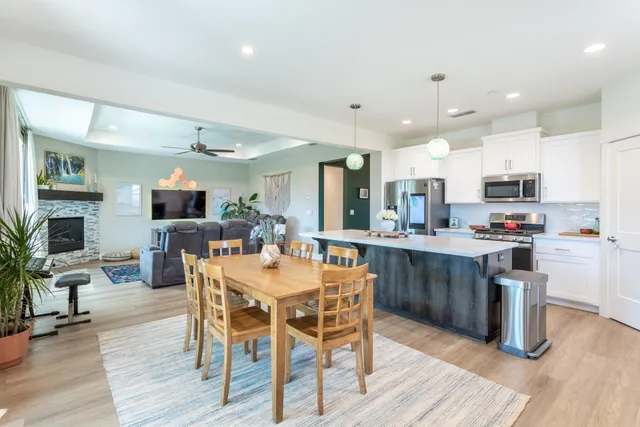 a kitchen with stainless steel appliances kitchen island granite countertop a table chairs and a refrigerator