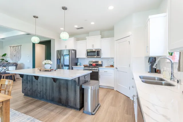 a kitchen with kitchen island granite countertop a sink appliances and cabinets