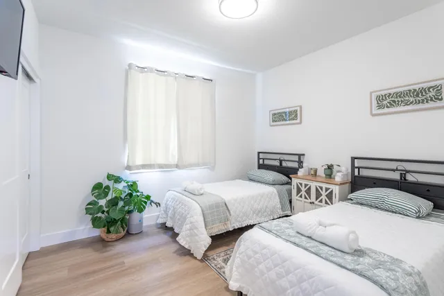 a bedroom with two beds and a potted plant