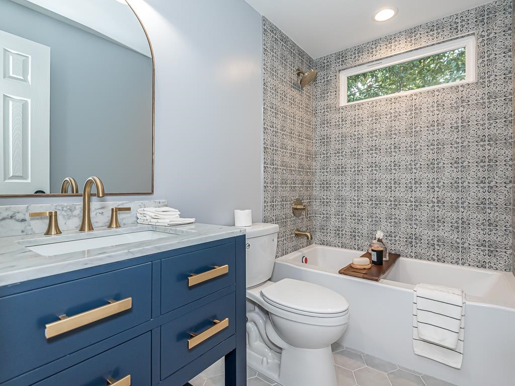 1703 Patton Road Raleigh, NC 27608 - Photo 14 of 30 a bathroom with a granite countertop toilet a sink a mirror and a shower