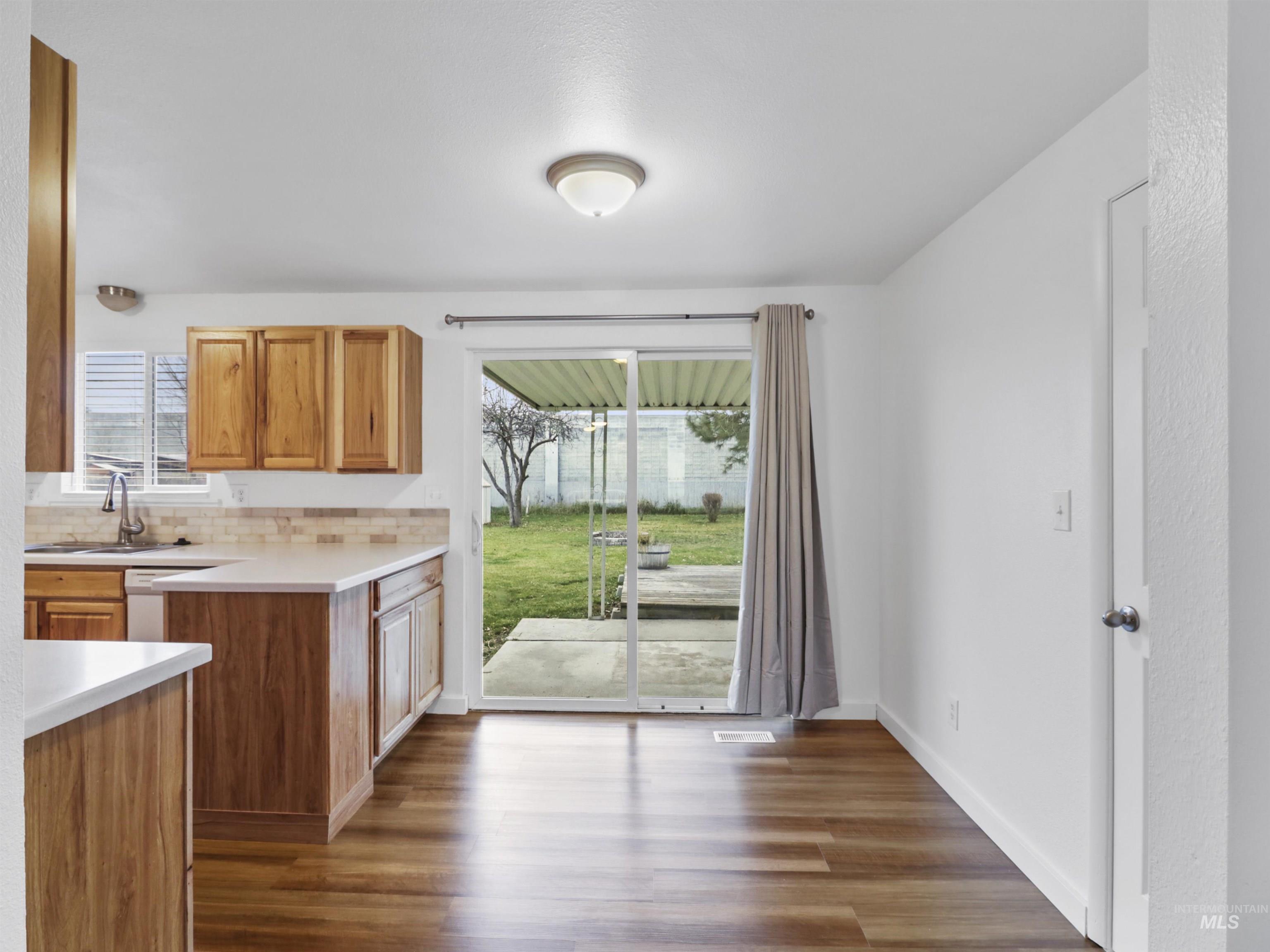 6739 West Grunder Street Boise, ID 83709 - Photo 12 of 24 Kitchen featuring light countertops, brown cabinets, dark wood-style floors, and tasteful backsplash