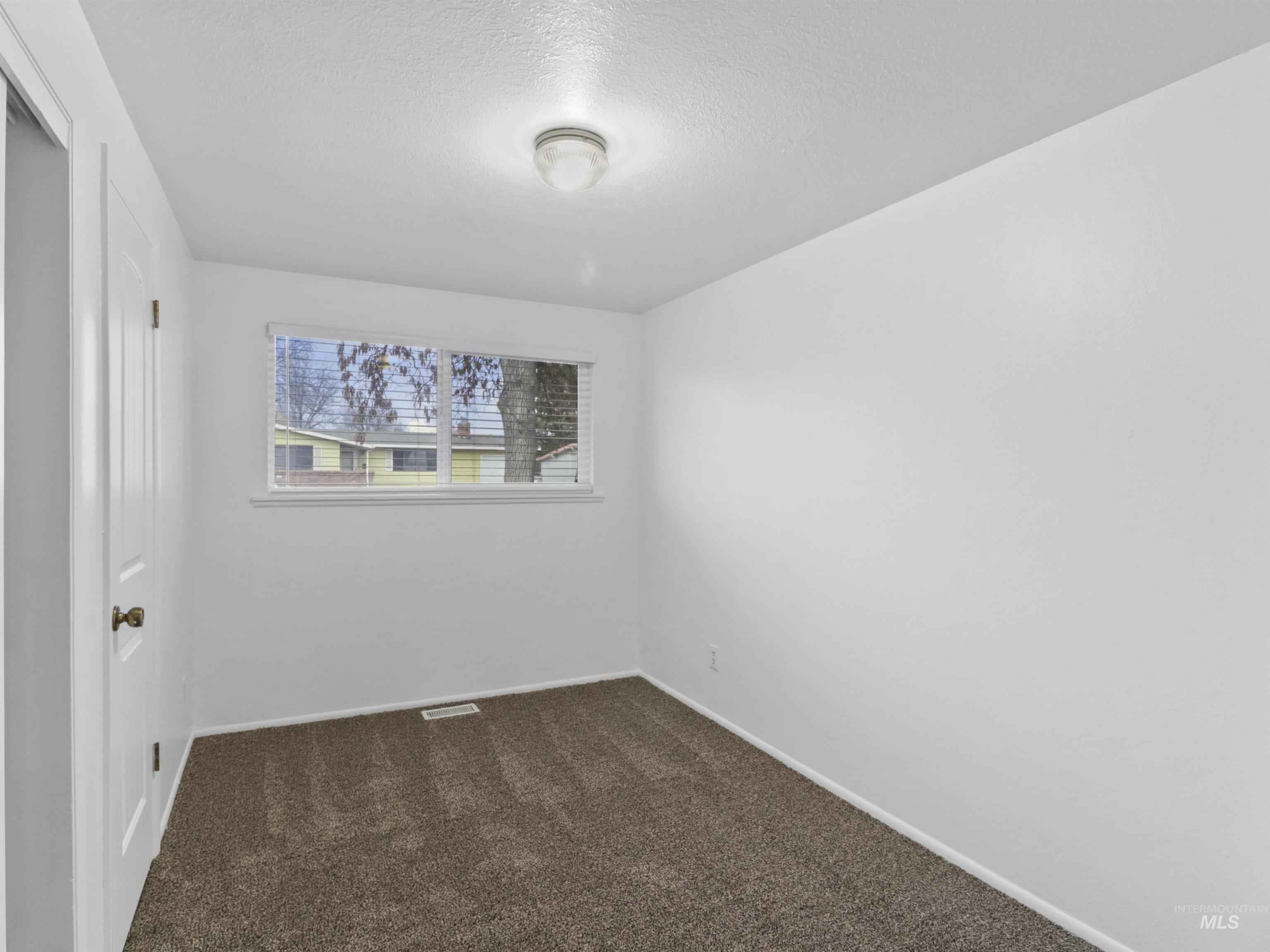 6739 West Grunder Street Boise, ID 83709 - Photo 13 of 24 Spare room featuring dark carpet and a textured ceiling