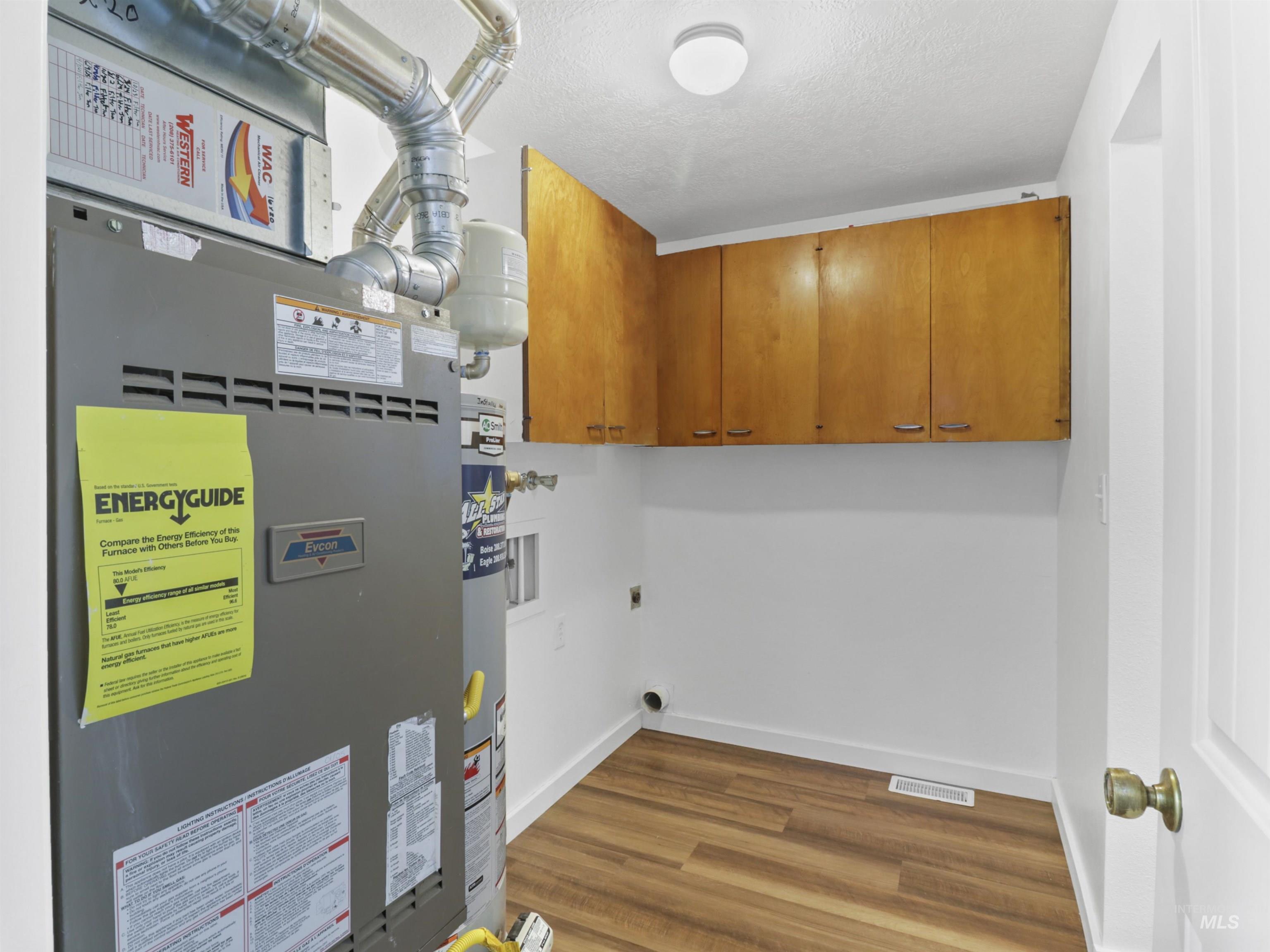 6739 West Grunder Street Boise, ID 83709 - Photo 21 of 24 Laundry area featuring heating unit, dark wood-style flooring, cabinet space, electric dryer hookup, and a textured ceiling