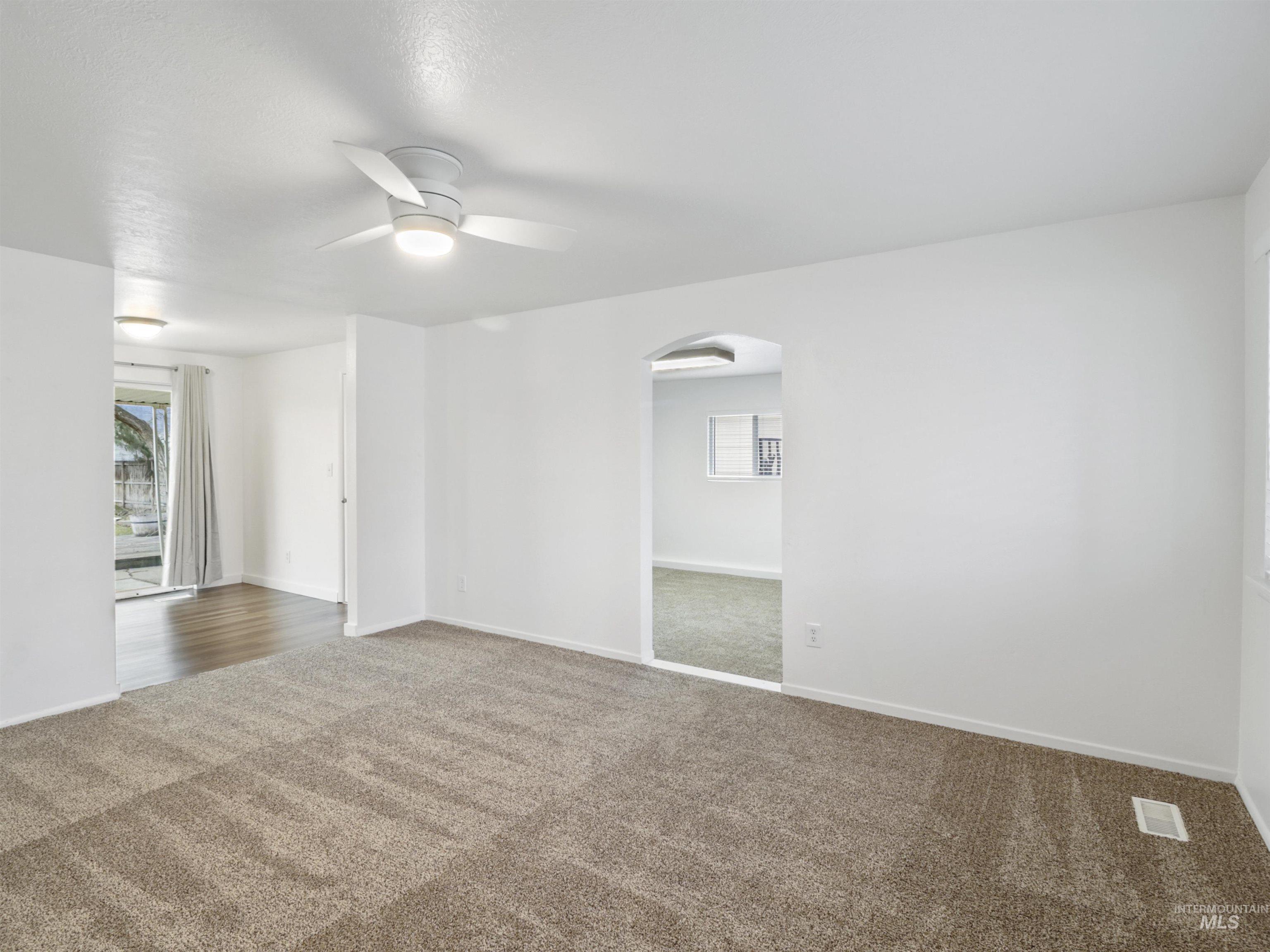 6739 West Grunder Street Boise, ID 83709 - Photo 4 of 24 Carpeted empty room featuring arched walkways, ceiling fan, and healthy amount of natural light