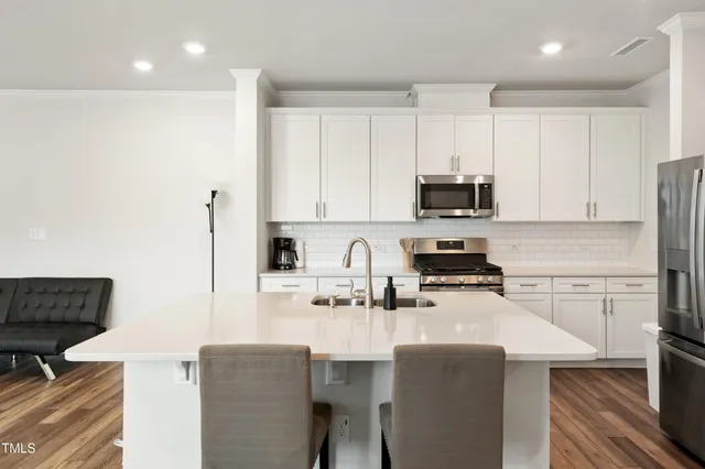 a kitchen with stainless steel appliances a stove a sink a refrigerator and white cabinets