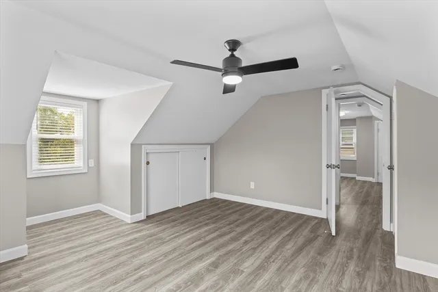an empty room with wooden floor a ceiling fan and windows