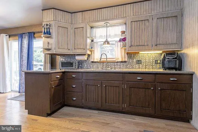 a kitchen with stainless steel appliances granite countertop wooden cabinets a sink and dishwasher with wooden floor