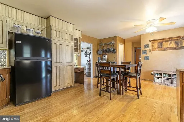 a kitchen with stainless steel appliances granite countertop a refrigerator a stove and a dining table with wooden floor