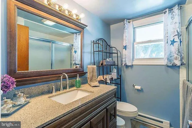 a bathroom with a granite countertop toilet sink and mirror