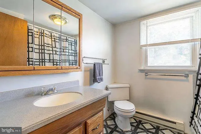 a bathroom with a granite countertop sink toilet and mirror