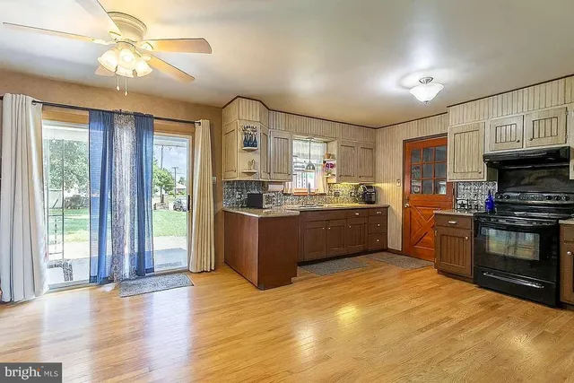 a kitchen with stainless steel appliances kitchen island granite countertop a stove a sink dishwasher a refrigerator and a dining table with wooden floor