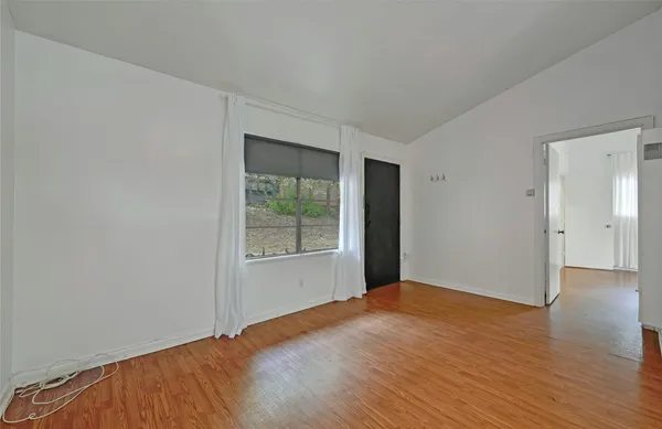 a view of an empty room with wooden floor and a window