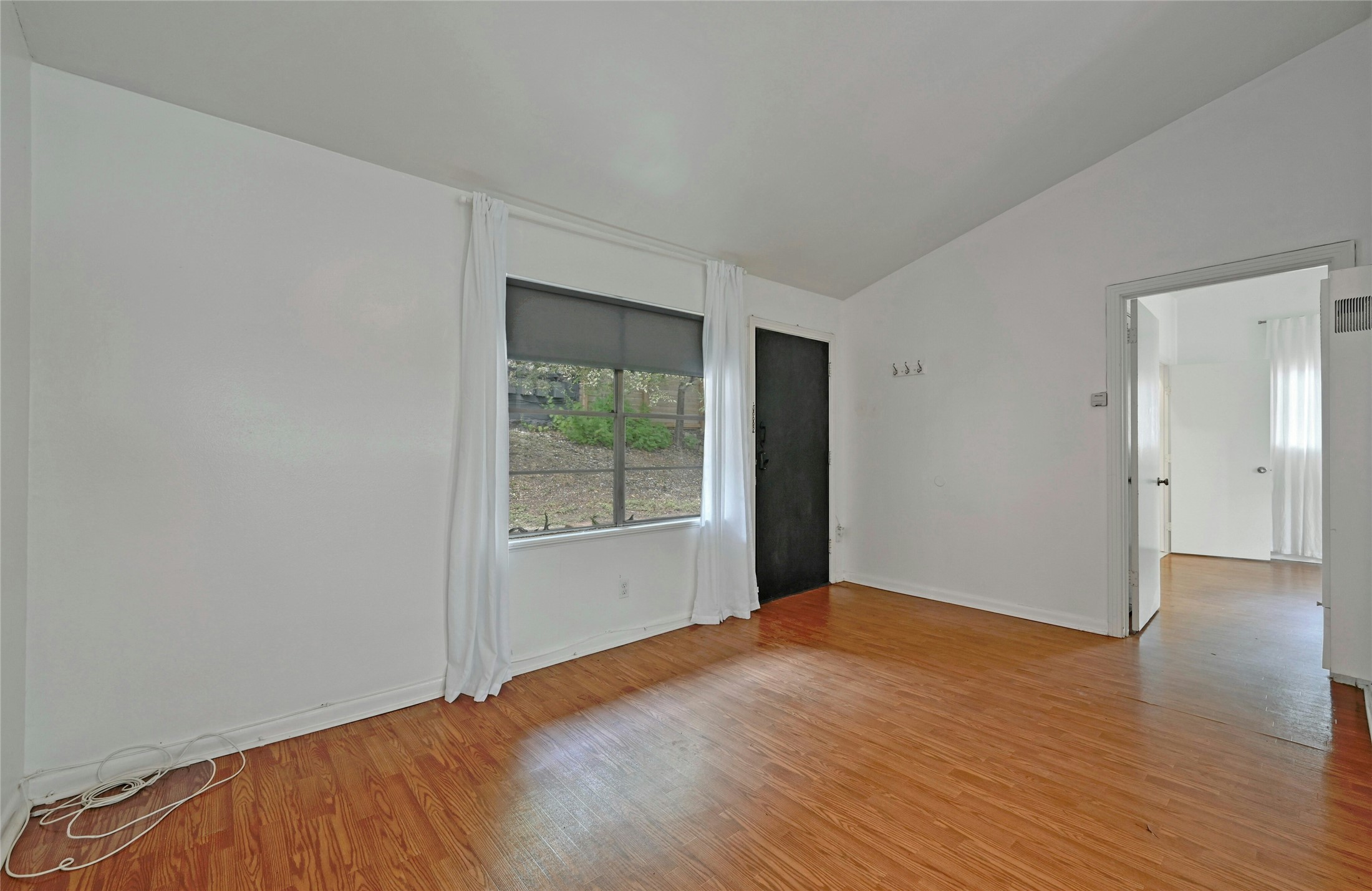 515 Pecan Grove Road, Unit A Austin, TX 78704 - Photo 4 of 17 a view of an empty room with wooden floor and a window