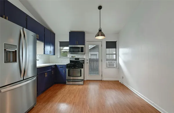 a kitchen with stainless steel appliances a refrigerator and a wooden floor