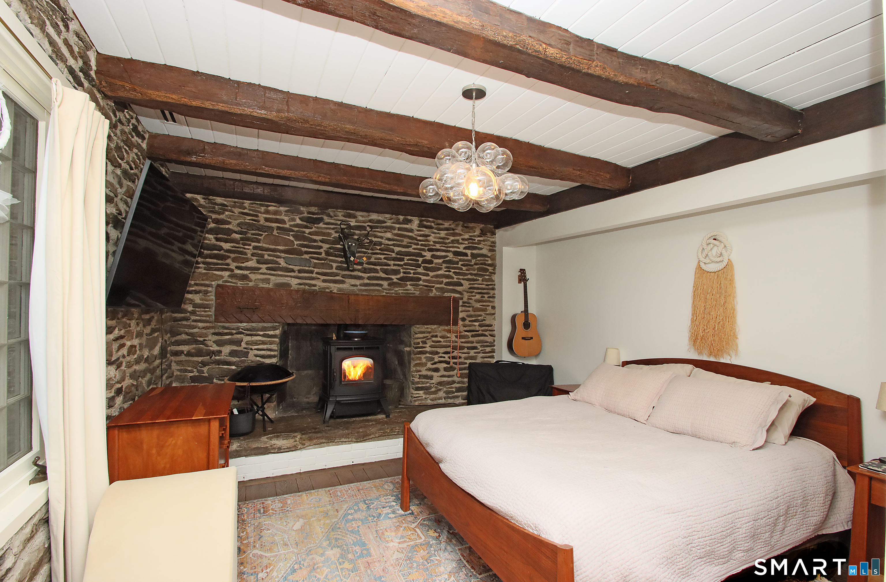 455 Barn Hill Road Monroe, CT 06468 - Photo 18 of 34 Main level primary suite with full bath, beamed ceiling, beautiful accent fireplace and pellet stove. Central air