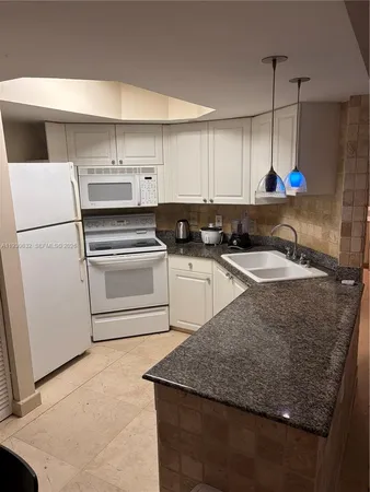 a kitchen with granite countertop a sink a stove and a refrigerator